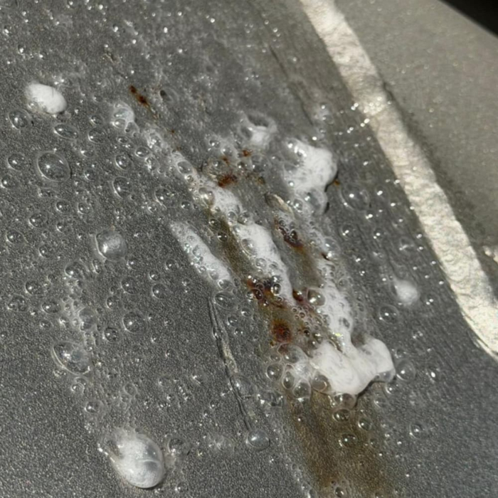 Close-up of rust and blistering on a stainless steel surface caused by chemical attack