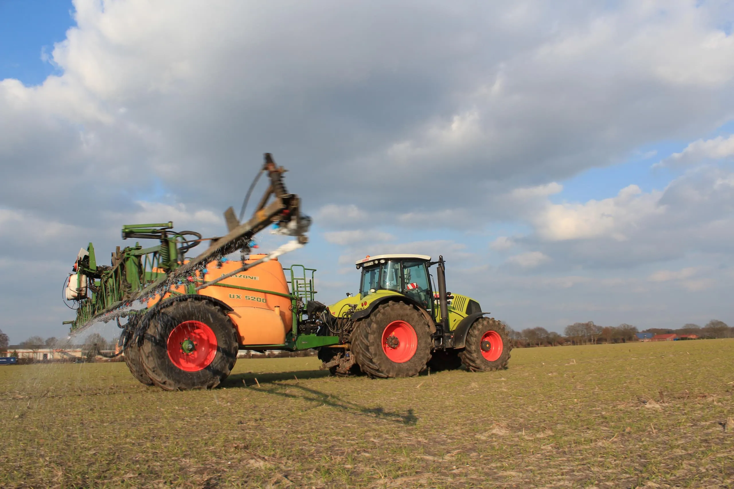 Claas tractor with Amazone UX 5200 trailed field sprayer applying AHL on a field