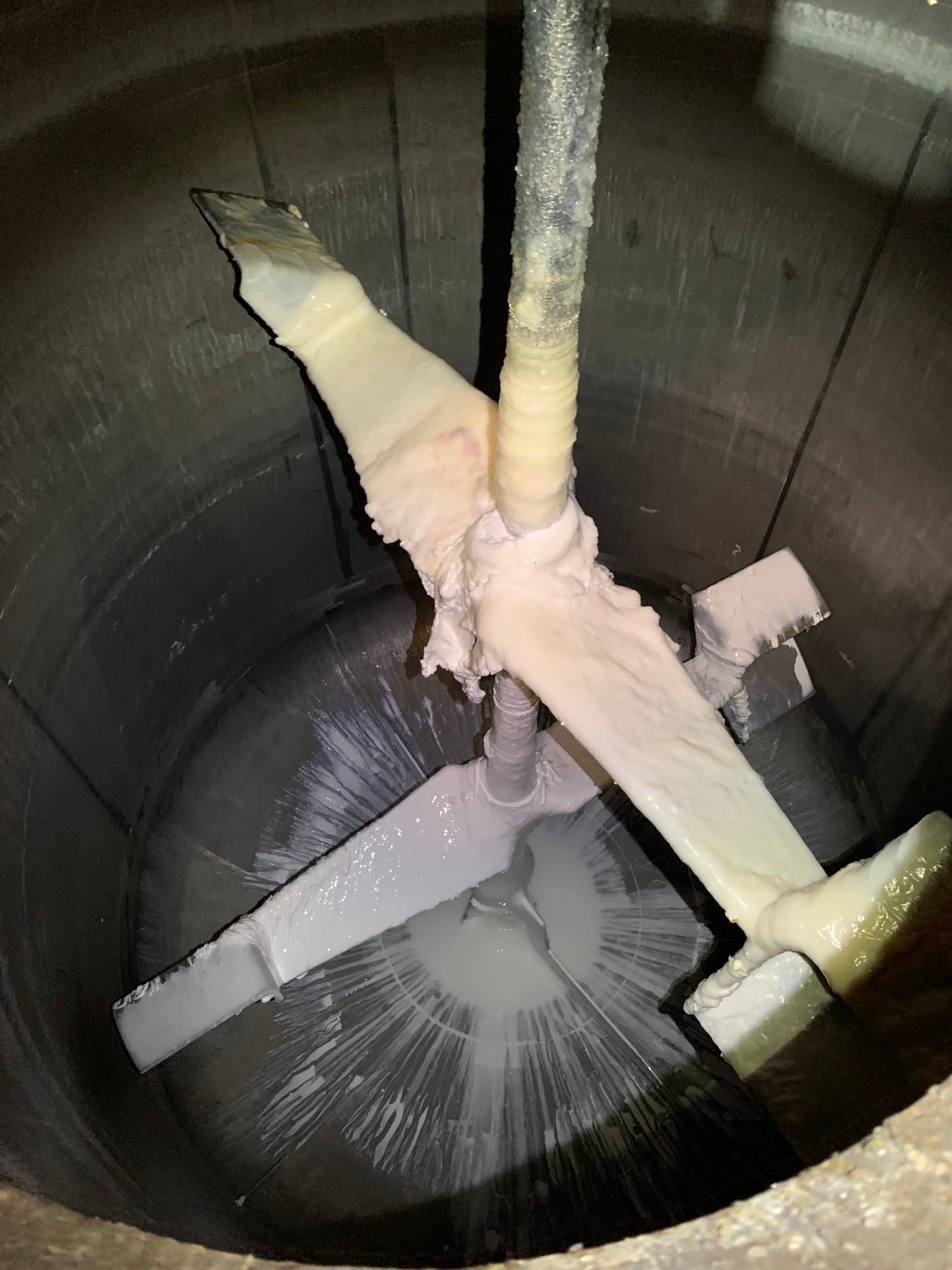 Vista interna di un serbatoio in acciaio inox con vaiolatura e fuoriuscita di sostanza sulle pale dell'agitatore