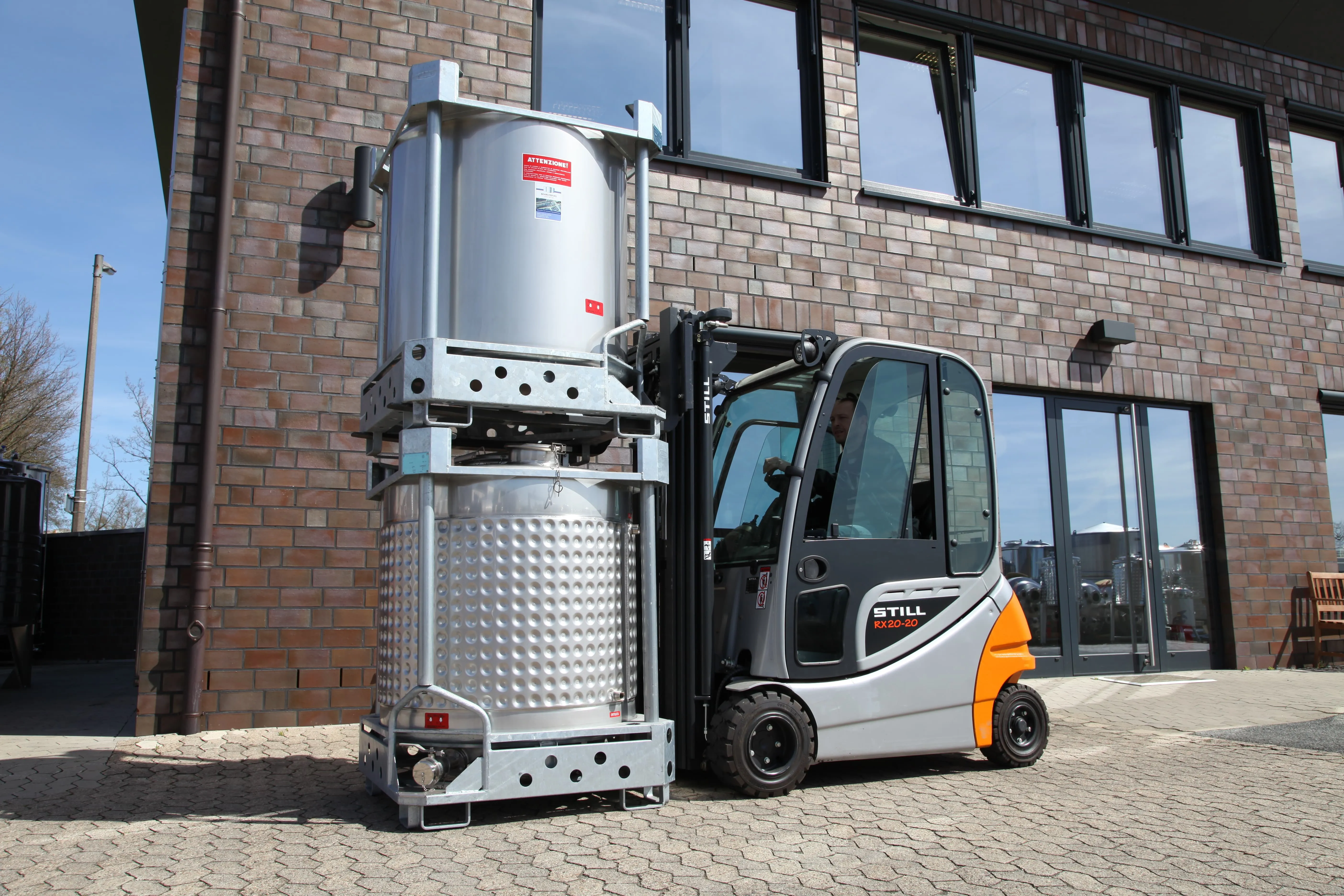 Transport eines Edelstahl IBC Beh&auml;lters mit Gabelstapler vor Industriegeb&auml;ude